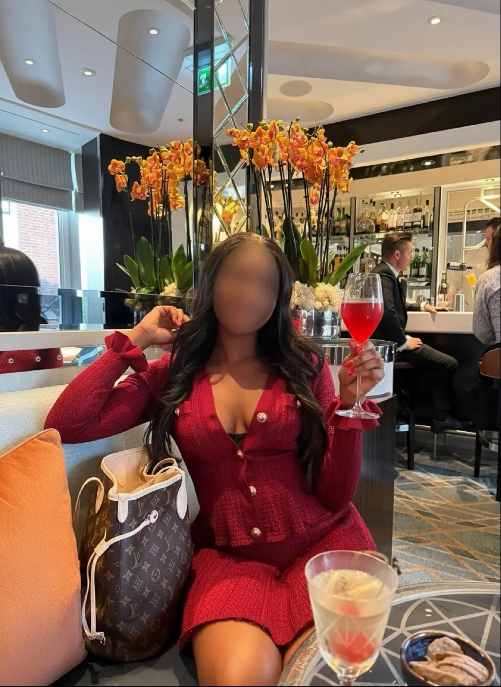 Woman in red outfit holding a drink in a bar.